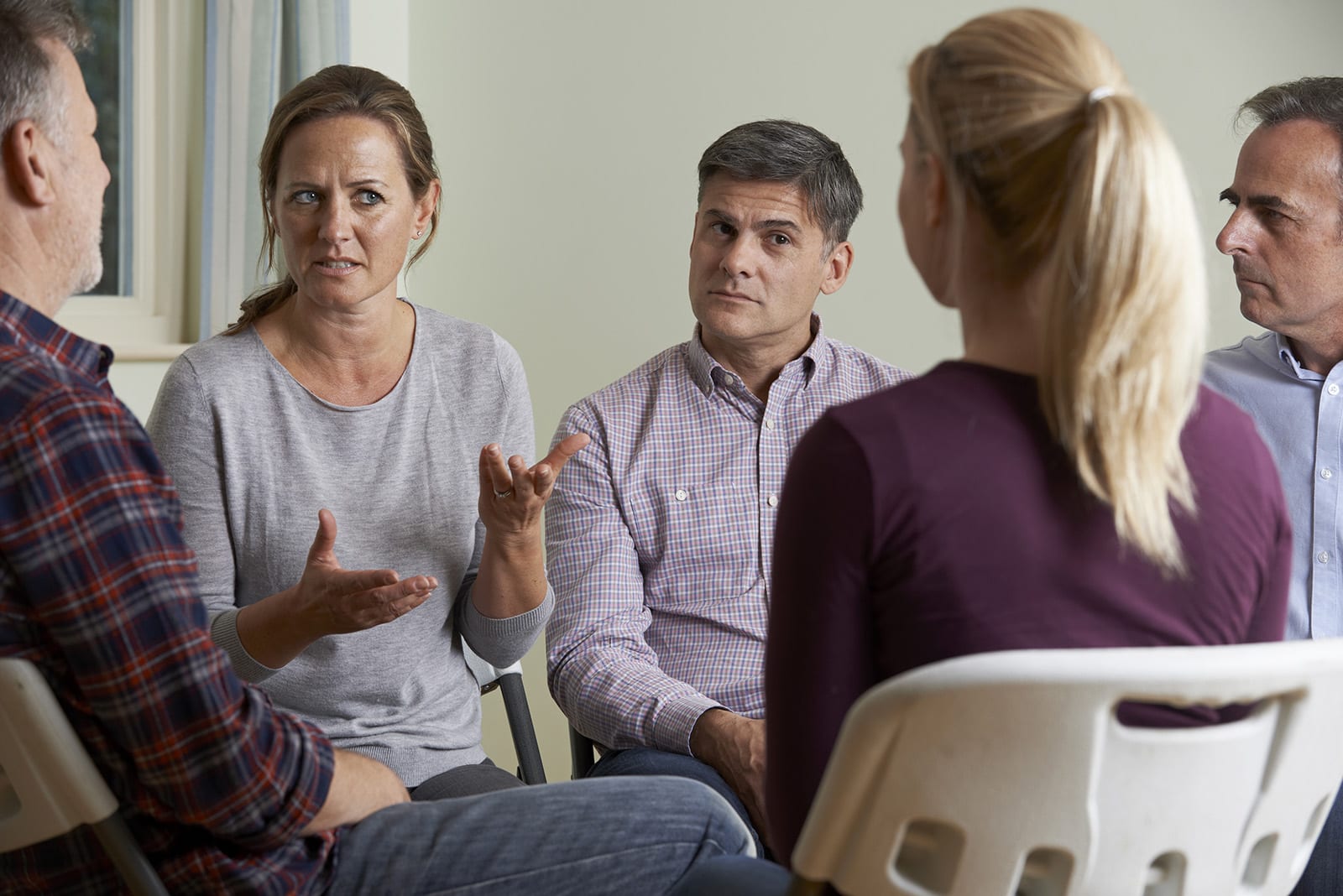 Members Of Support Group Sitting In Chairs Having Meeting